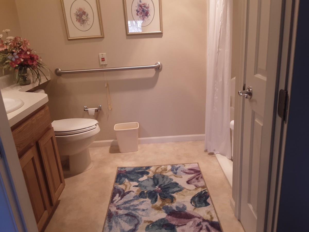 A neatly organized bathroom with floral decor and a colorful rug.