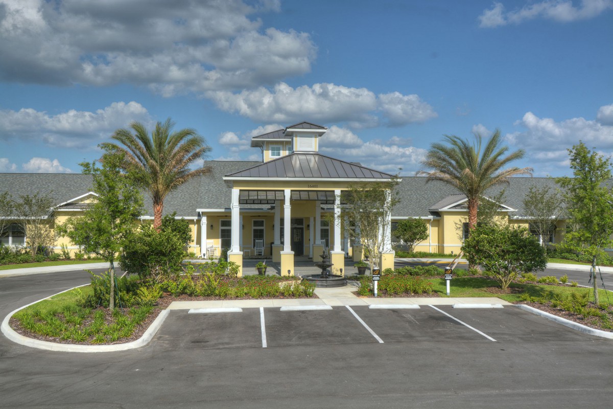 A sunny view of a modern building with palm trees and a clear sky.