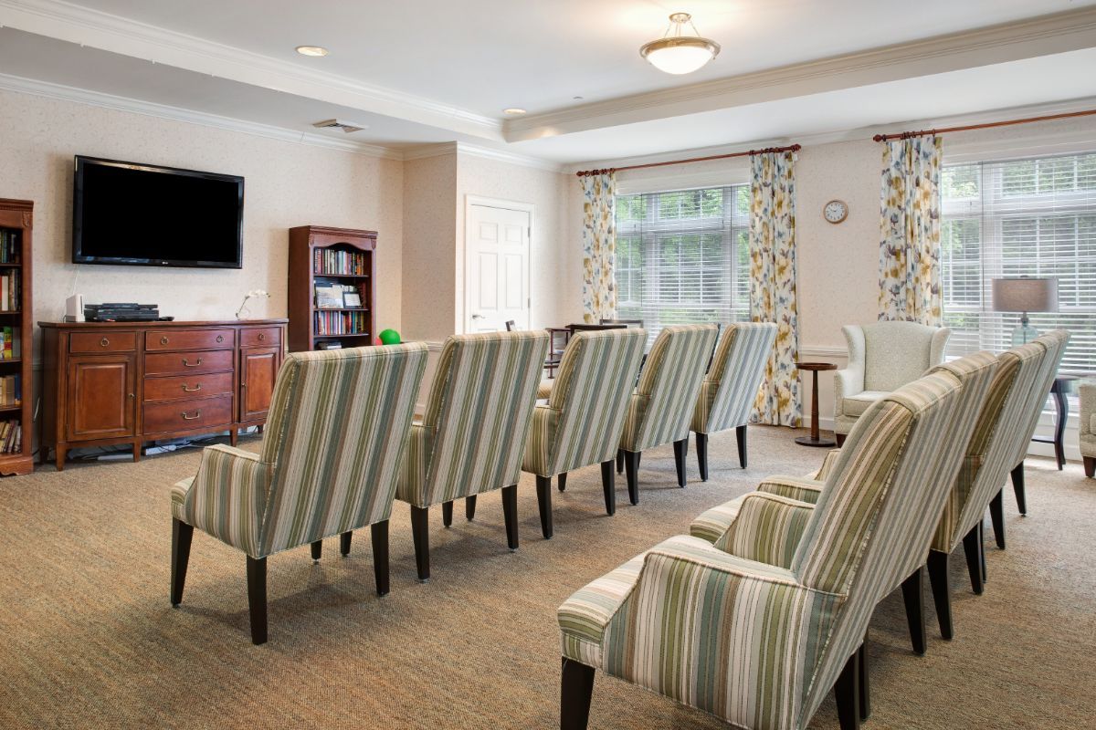 A neatly arranged meeting room with striped chairs, a television, and a bookshelf.