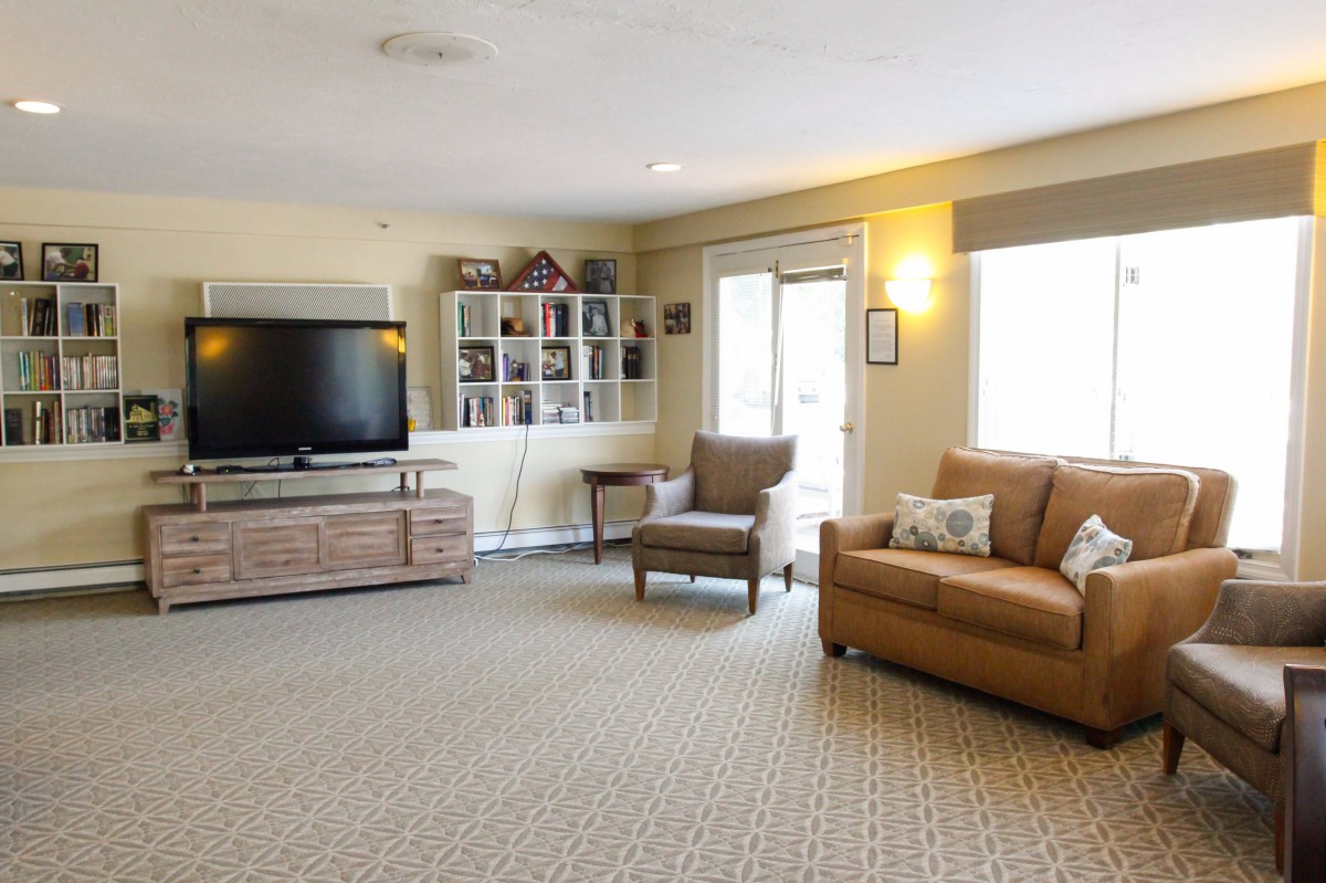 A cozy living room with a sofa, armchair, and a large television.