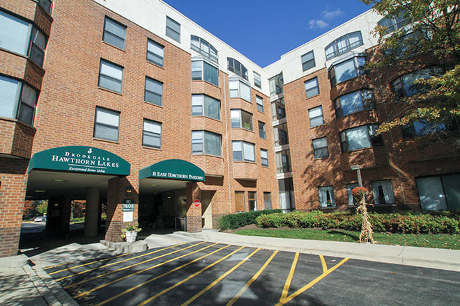 A modern urban apartment building with a brick exterior and green awnings.