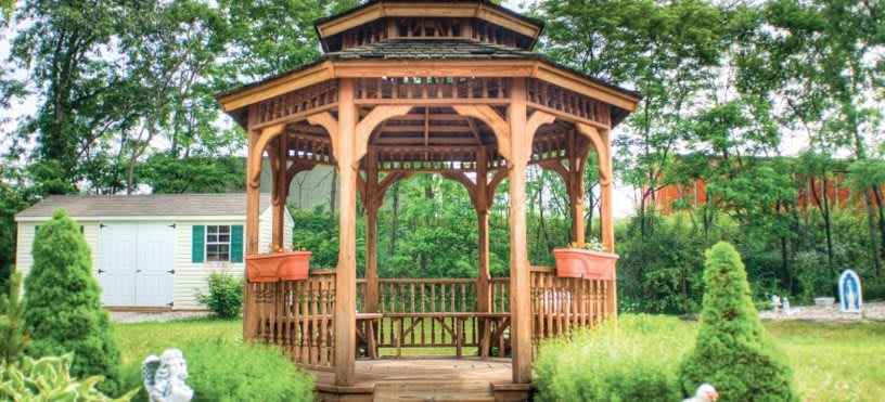 A wooden gazebo surrounded by lush greenery.