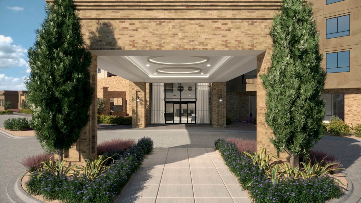 Entrance to a modern building with columns and landscaped walkway.