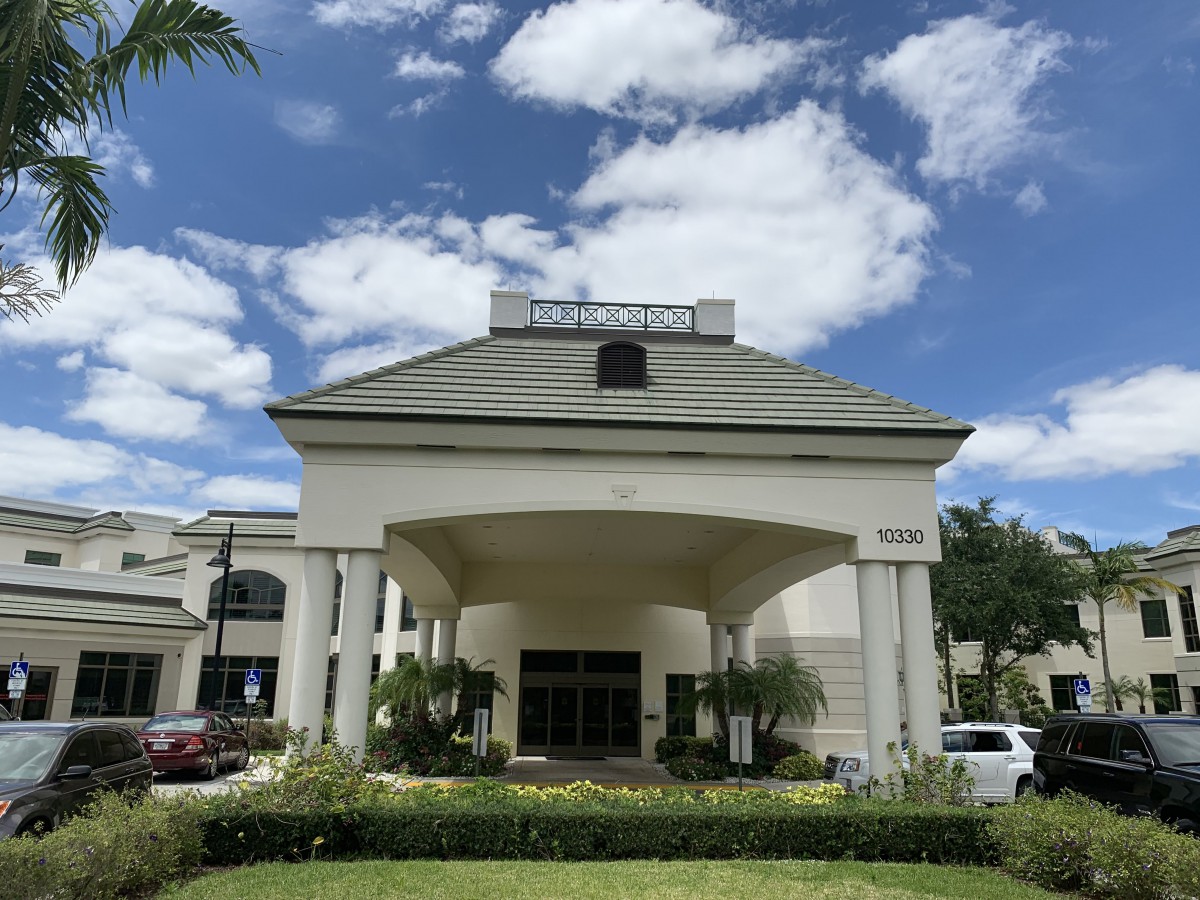 A large building entrance with columns under a partly cloudy sky.