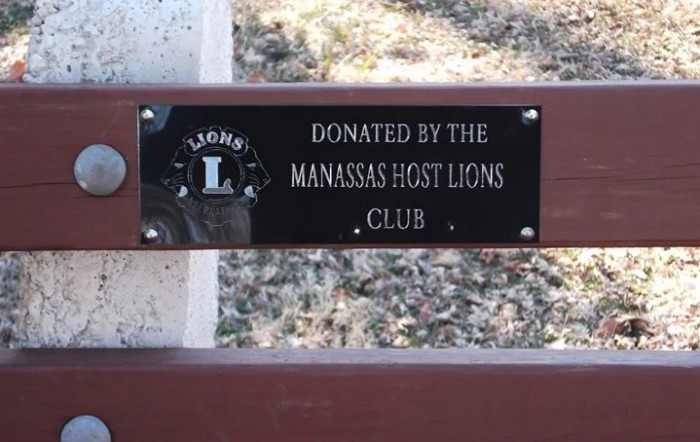 A plaque on a bench indicating it was donated by the Manassas Host Lions Club.