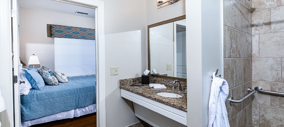 A hotel bathroom vanity area with a sink, mirror, and neatly arranged towels.