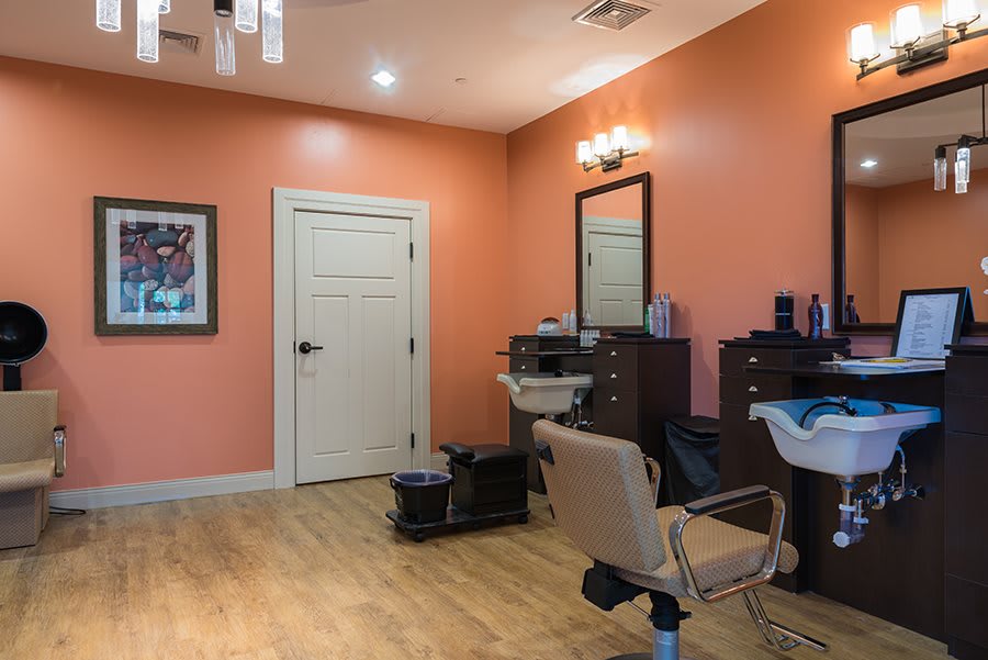 A cozy salon interior with an orange color scheme, featuring a hairdressing chair and mirror.