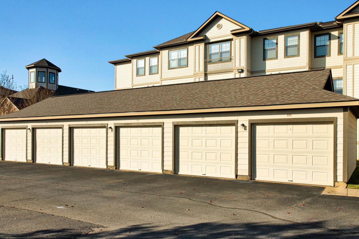 A row of garages beneath a residential townhouse complex on a sunny day.