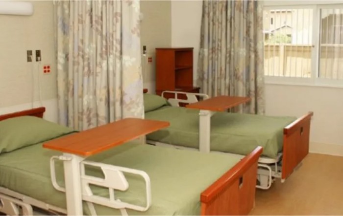 A hospital room with two neatly arranged beds and privacy curtains.
