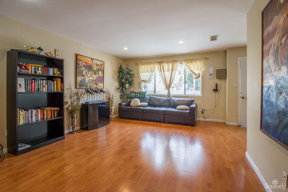 A cozy living room with a sofa, bookshelf, and hardwood flooring.