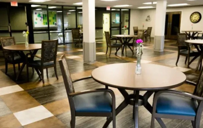 A modern dining area with tables and chairs, featuring a vase with flowers on a table.