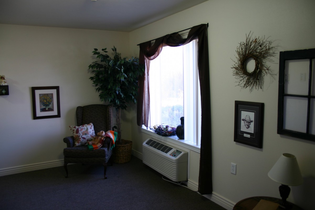 A cozy living room corner with a chair, window, and decorative elements.