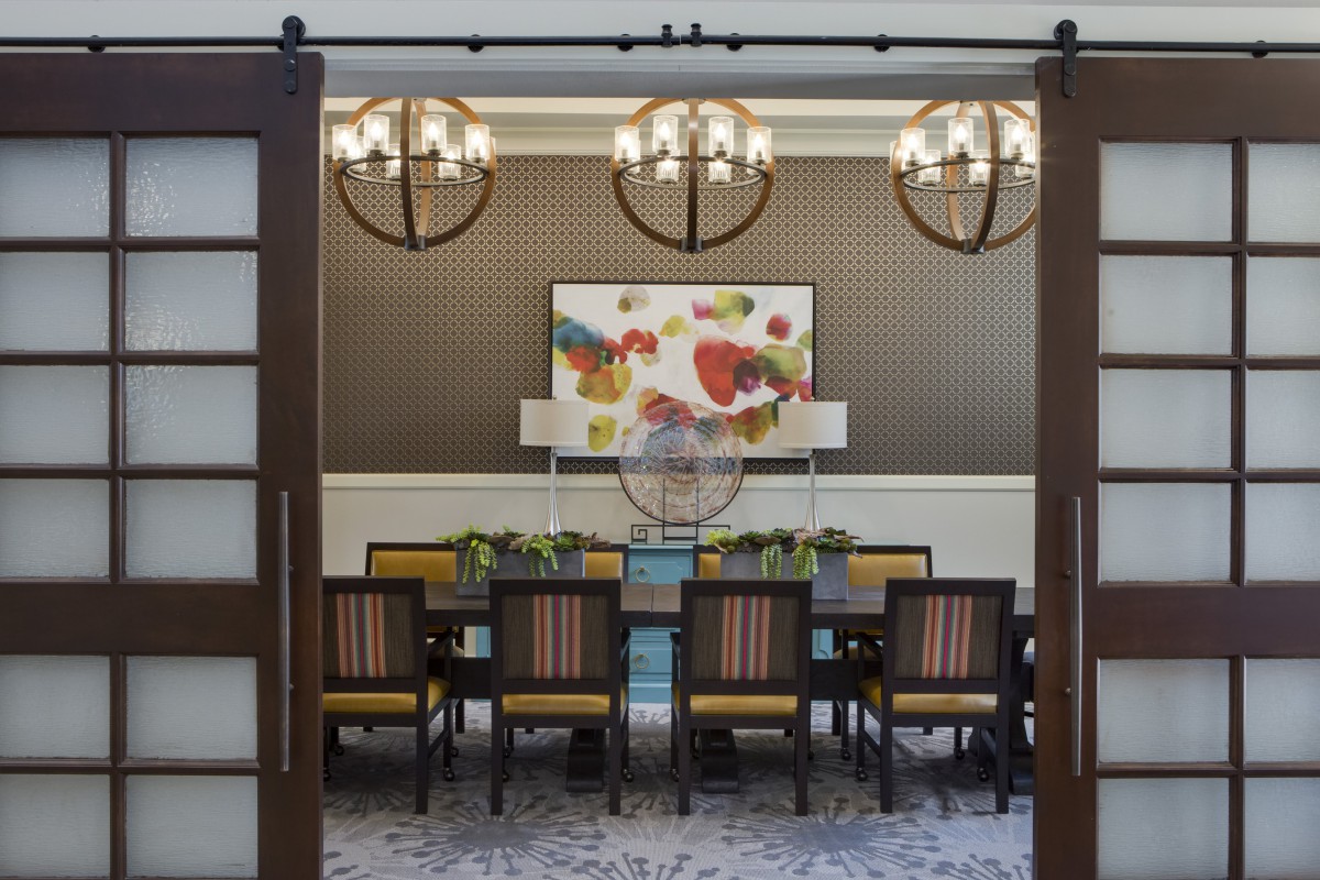 A modern dining room with elegant chandeliers and colorful artwork.