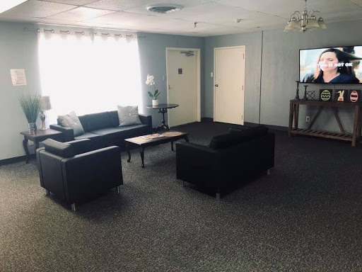A cozy lounge area featuring black sofas and a coffee table, illuminated by natural light.