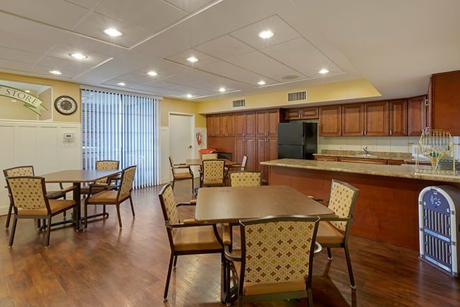 A spacious kitchen and dining area with wooden cabinetry, several tables, and chairs.