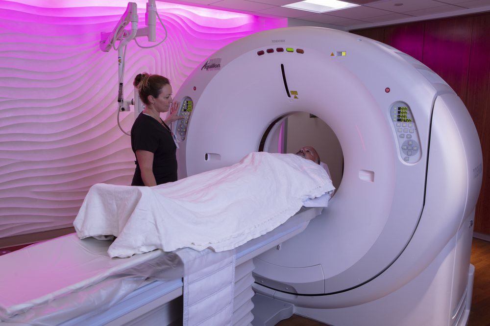 A healthcare professional operates an MRI machine for a patient.