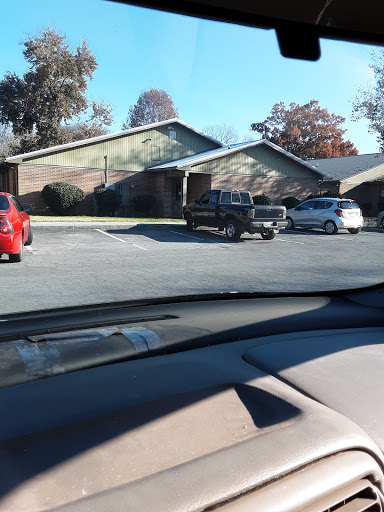 A view of a parking area in front of residential buildings, showcasing various vehicles parked.