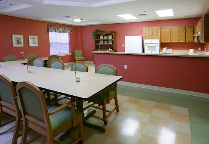 A cozy dining and kitchen area with a large table and chairs, set against warm red walls.