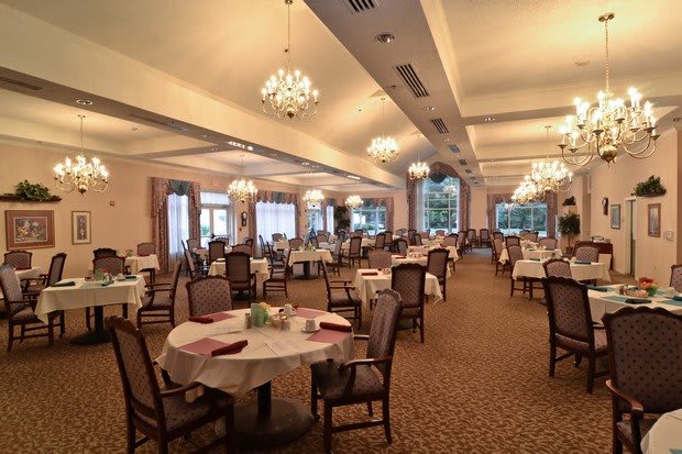 An elegant dining room with chandeliers and neatly arranged tables and chairs.
