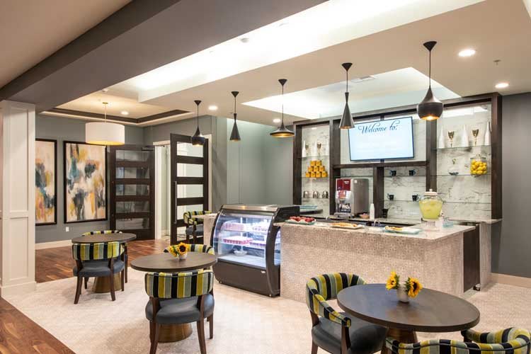 A modern cafe interior featuring a stylish seating area and a sleek counter with a display case.