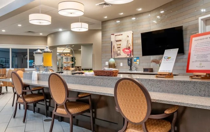 A modern lobby area featuring comfortable seating, a counter with chairs, stylish lighting, and a television.