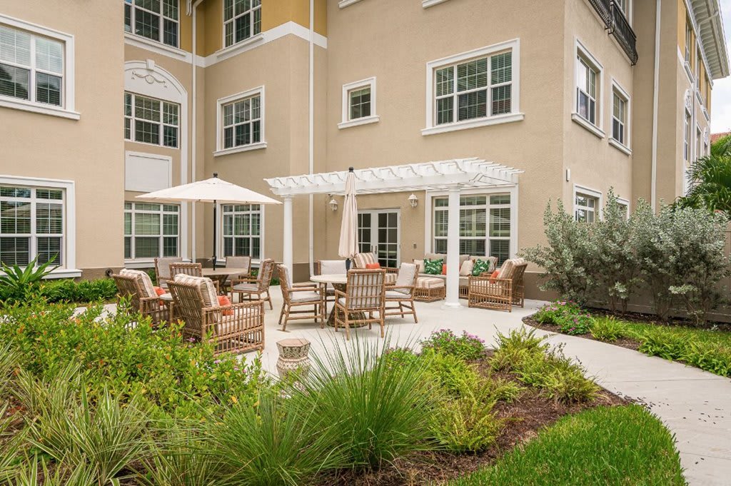 A patio area with outdoor furniture and a garden in front of a building.