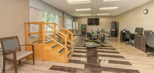 A modern gym space featuring exercise equipment and a set of stairs, designed for fitness and rehabilitation.