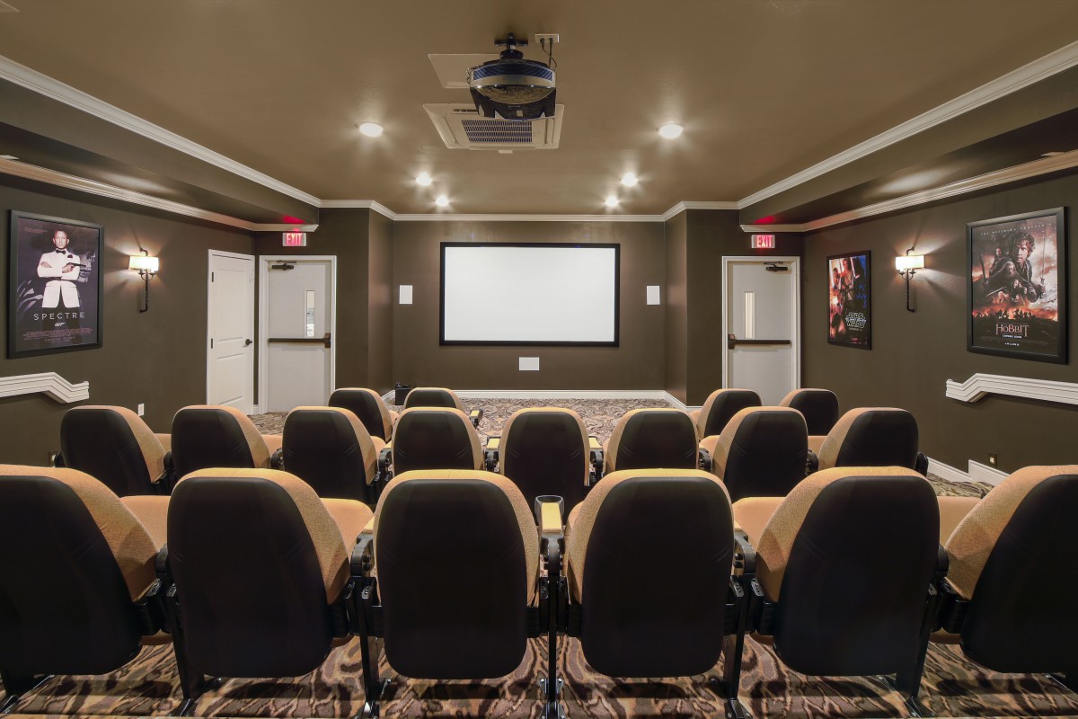 A cozy home theater setup with rows of seating facing a large projection screen.