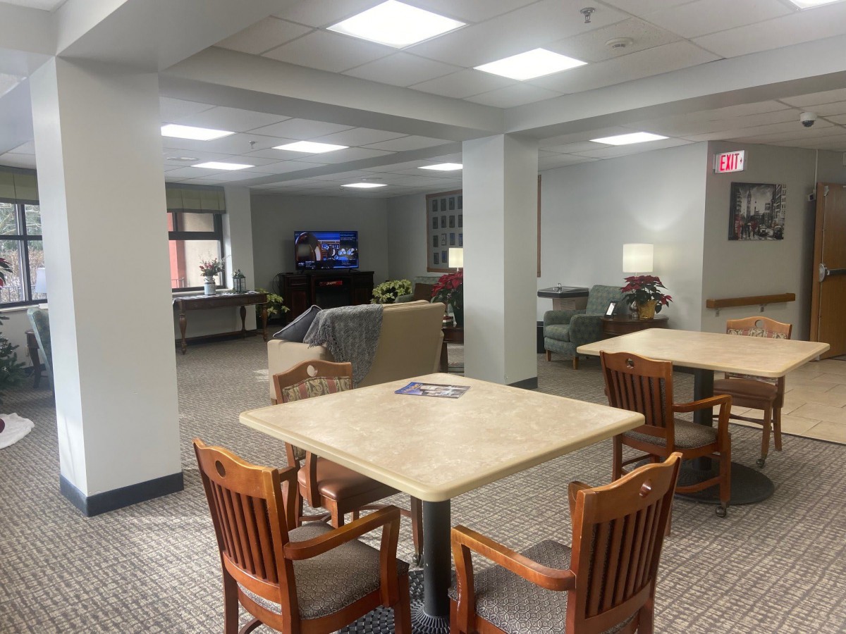 A cozy lounge area with tables, chairs, and a television.