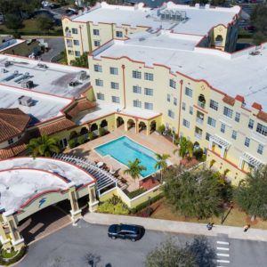 Aerial view of a hotel complex with a central swimming pool and surrounding landscaped area.