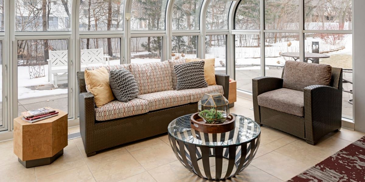 A modern living room with a comfortable sofa, stylish glass coffee table, and large windows allowing natural light.