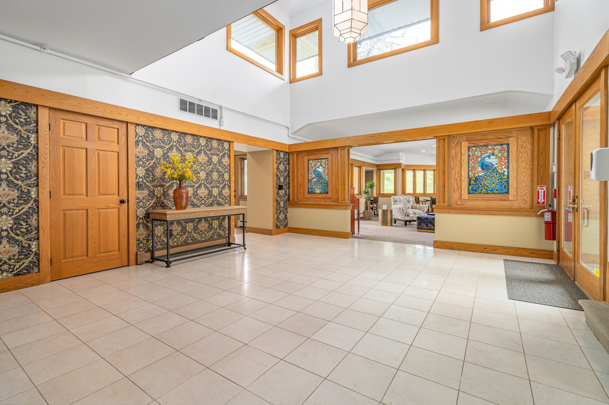 A modern and spacious entryway featuring a tile floor, natural light, and decorative artwork.