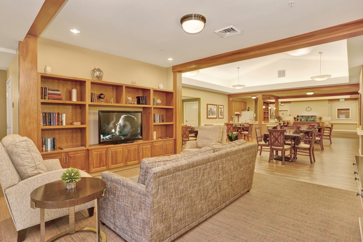 A cozy living room with a large sofa, built-in wooden bookshelves, and a television.
