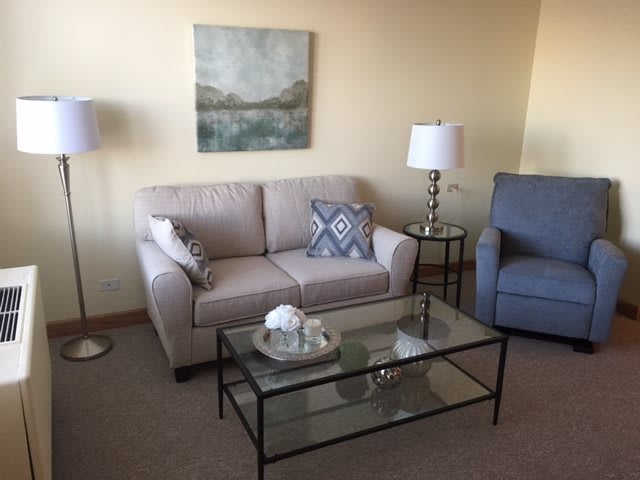 A cozy living room with a sofa, armchair, and glass coffee table.