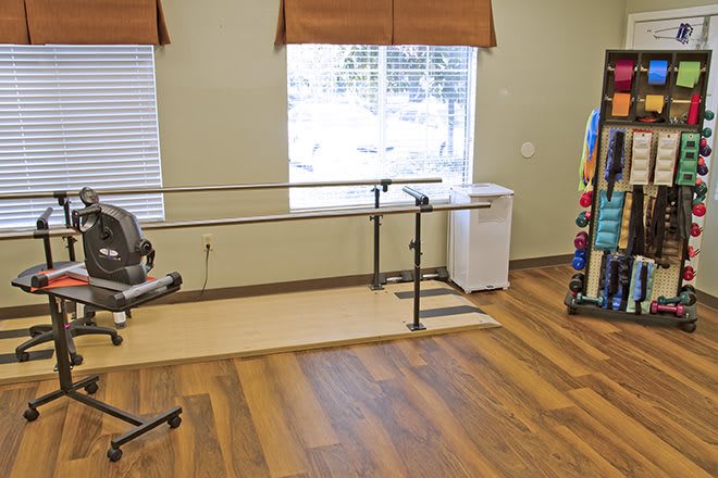 A physical therapy room with exercise equipment and parallel bars.
