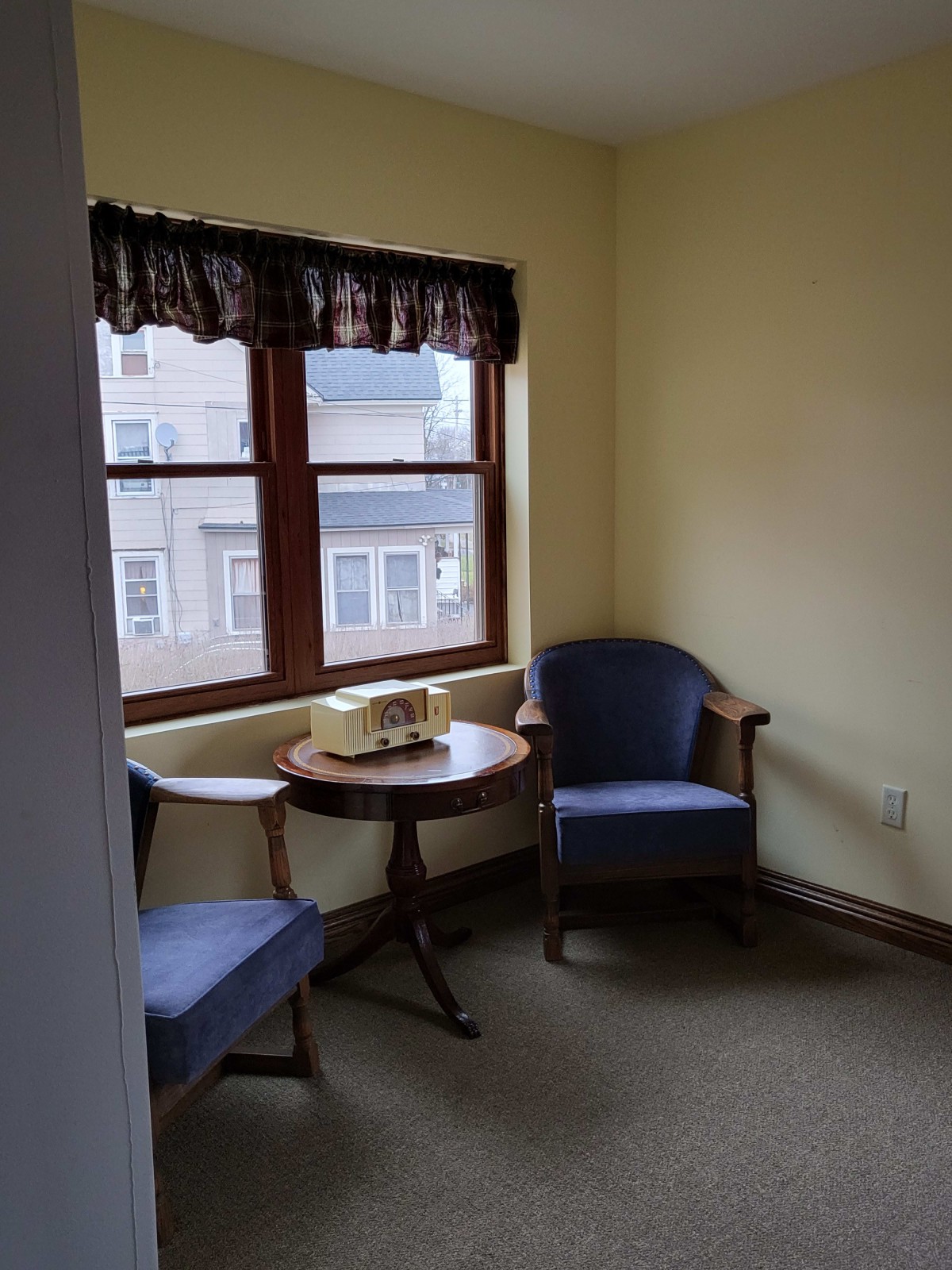 A cozy corner with two chairs, a wooden table, and an old-fashioned telephone by the window.
