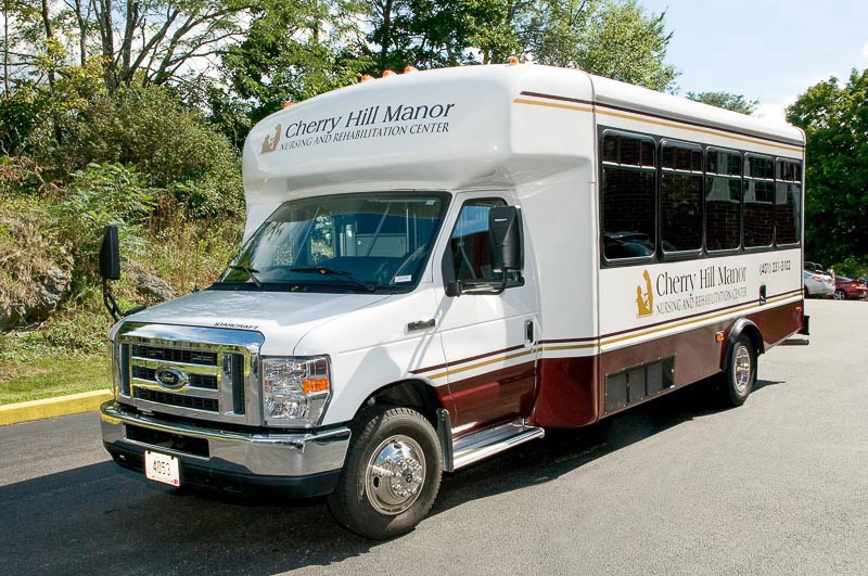 A shuttle bus parked outdoors, branded with Cherry Hill Manor.