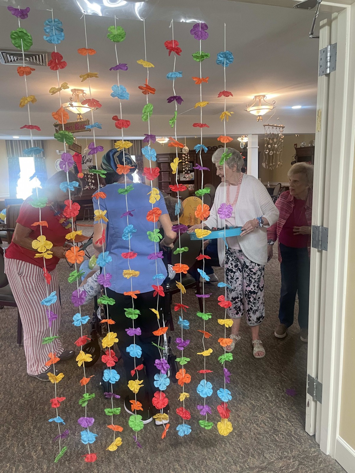 A festive indoor party with colorful hanging decorations and people gathered.