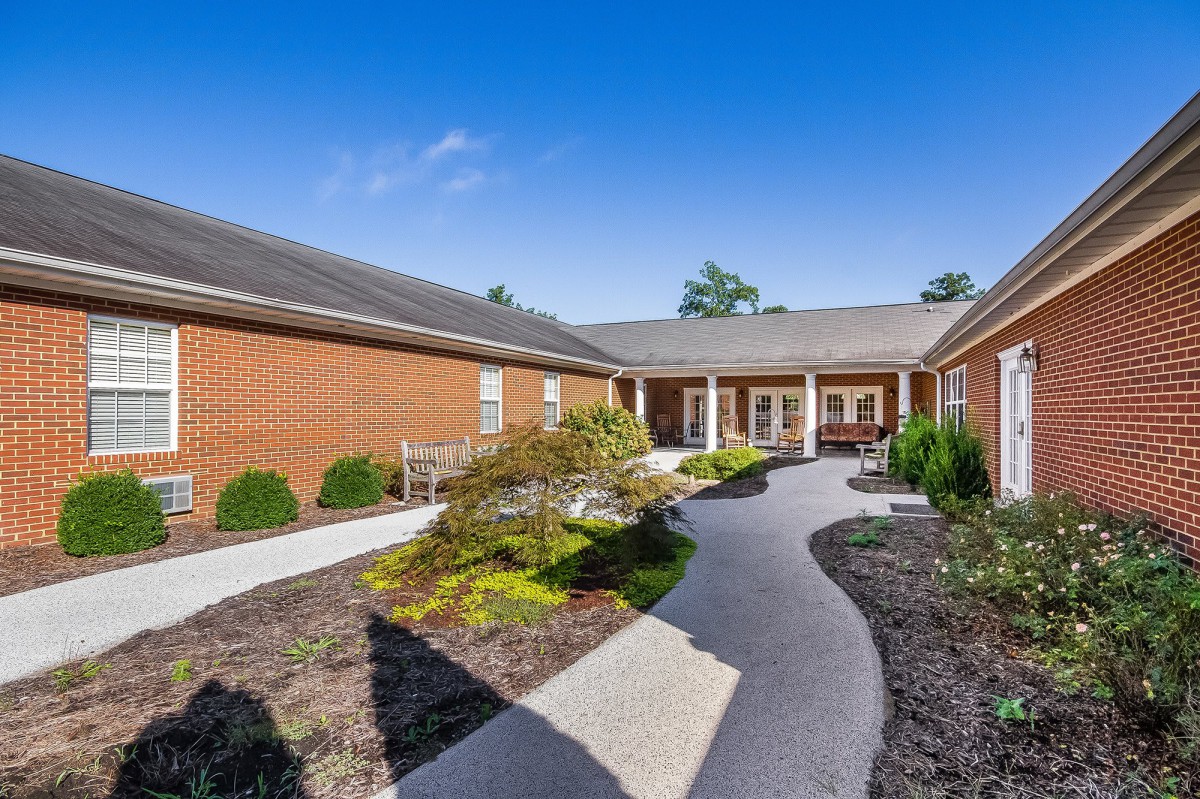 A well-maintained brick building with a curved pathway and landscaped greenery under a clear blue sky.