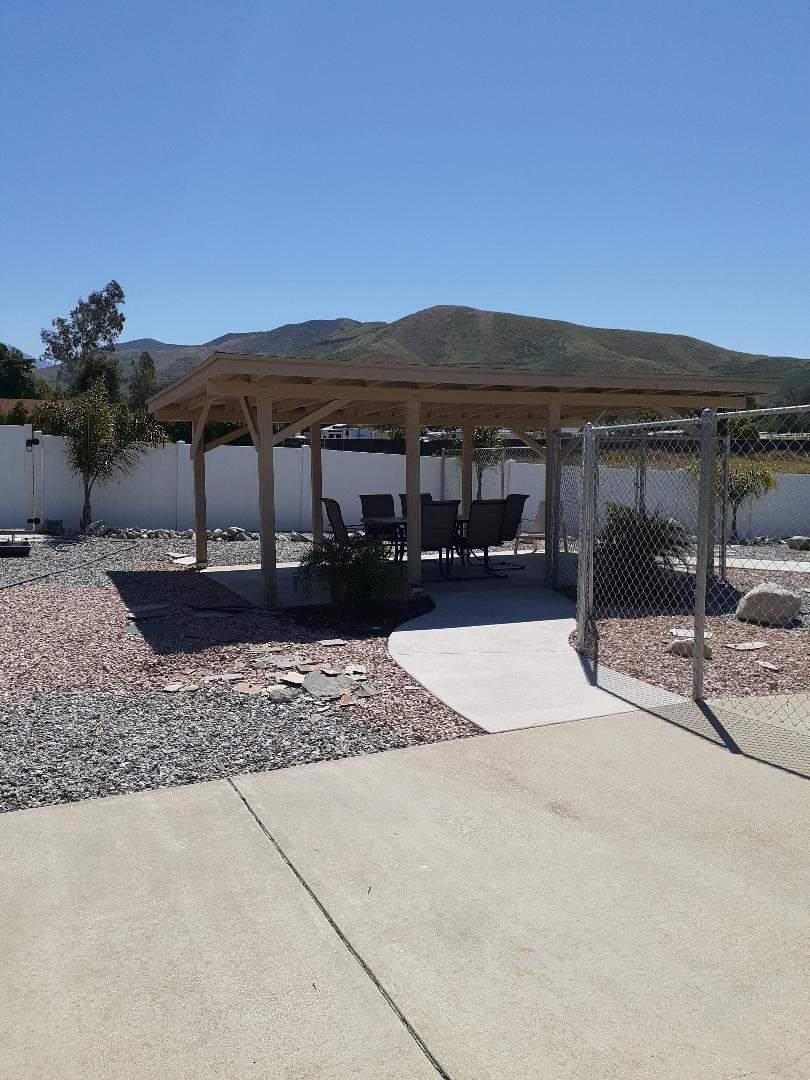 A backyard with a pergola and outdoor seating, set against a mountainous landscape.