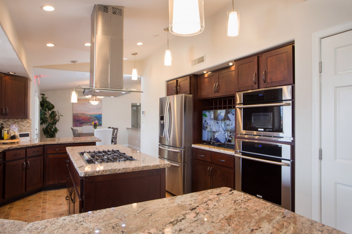 A modern kitchen with a central island, granite countertops, and stainless steel appliances.