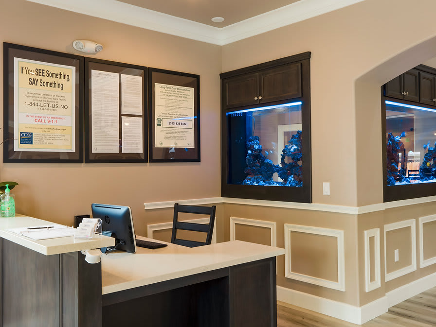 A modern office reception area with a desk, computer, and an aquarium.