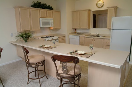 A spacious and modern kitchen featuring light-colored cabinets, a center island with bar stools, and essential appliances.