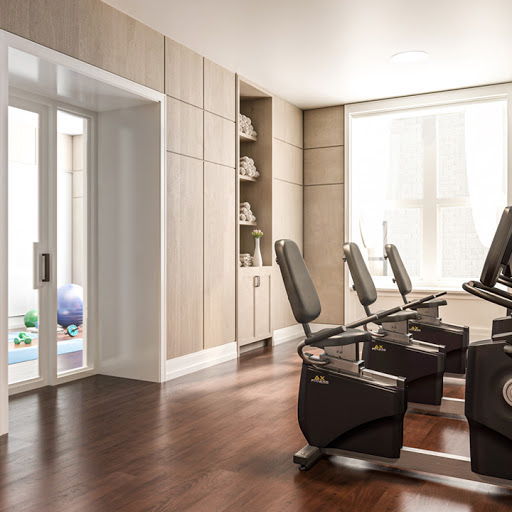 A sleek and modern fitness room featuring exercise equipment, enhanced by natural light and elegant wooden flooring.