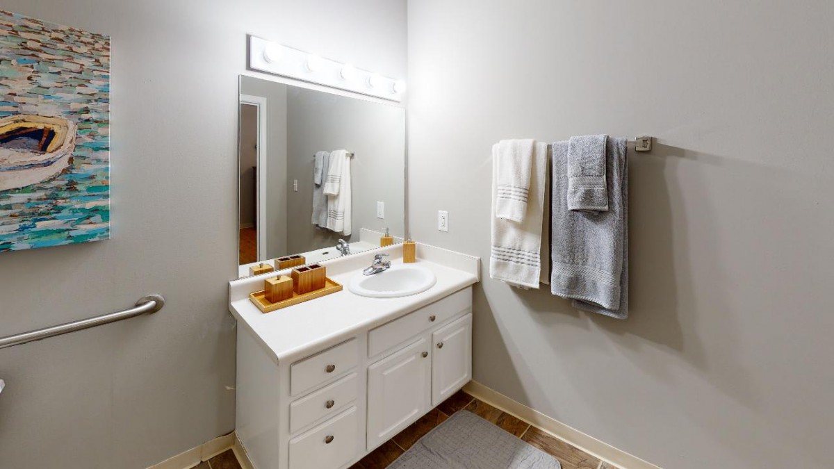 A neatly organized bathroom with a white vanity, mirror, and hanging towels.