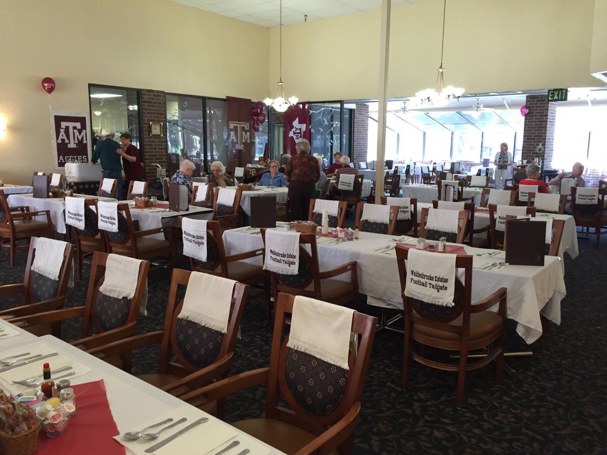 A spacious dining area with neatly arranged tables and chairs, each adorned with white tablecloths.