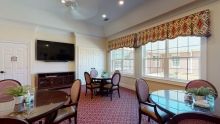 A conference room with tables, chairs, and a television.