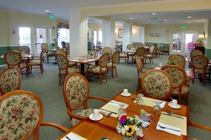 An empty dining room with elegantly set tables and floral decorations.