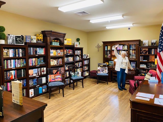A cozy bookstore with neatly arranged bookshelves and a wooden floor, featuring a reading area and a person browsing through the selections.
