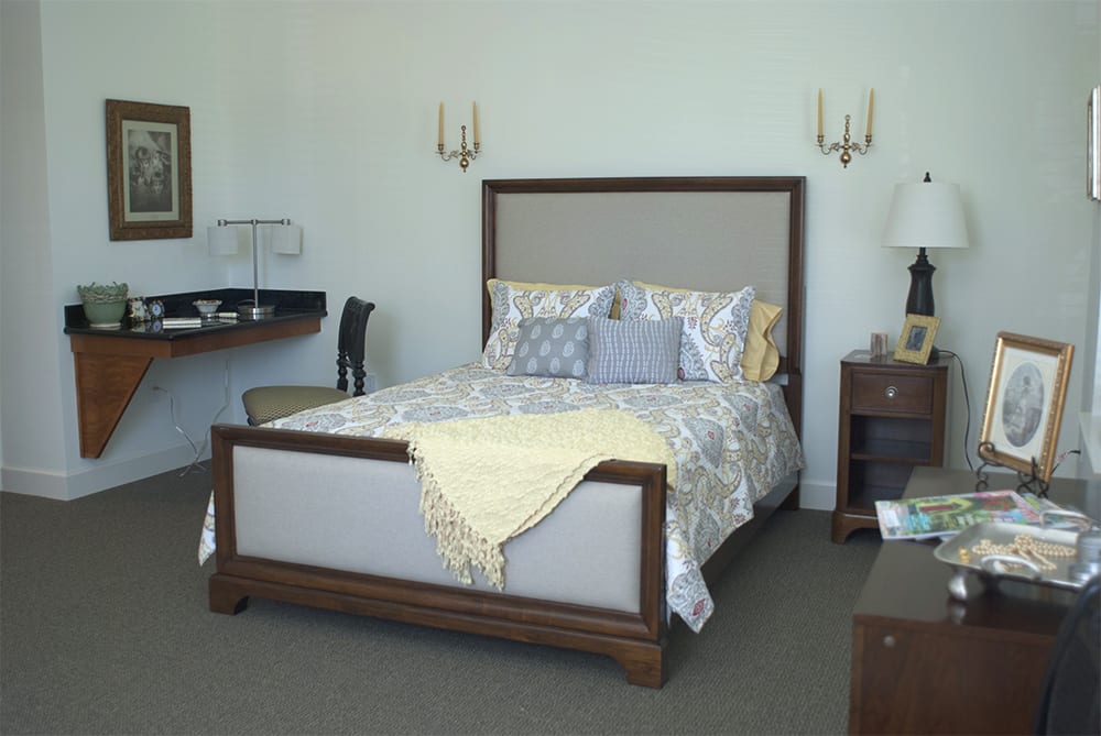 A well-decorated bedroom featuring a neatly made bed with elegant bedding, flanked by nightstands and lamps.